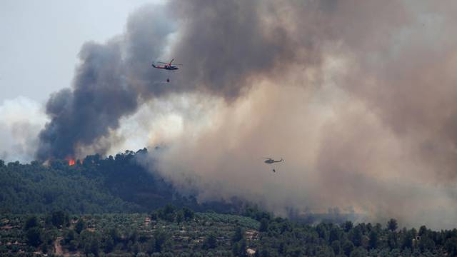 Helicopters drop water over a forest fire near Bovera