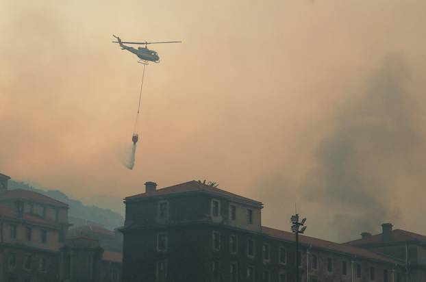 A helicopter drops water as the library at the University of Cape Town burns, in Cape Town