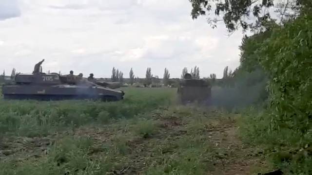 Ukrainian military members ride on howitzers in location given as Donbas region