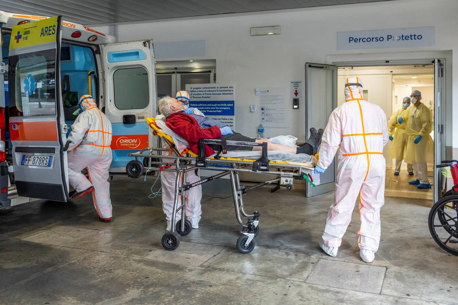 Medical workers in protective suits take an elderly coronavirus patient on a stretcher into an ambulance in the emergency room of the Gemelli Hospital, in Rome