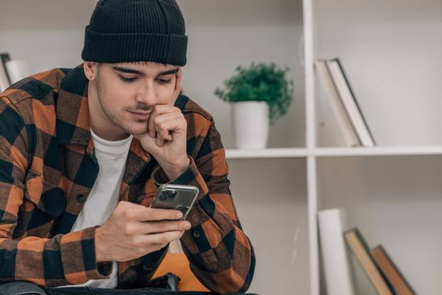young man at home sitting looking at mobile phone