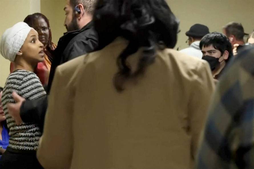 A security person holds back U.S. Rep. Ilhan Omar after a man disrupted a town hall meeting in Minneapolis