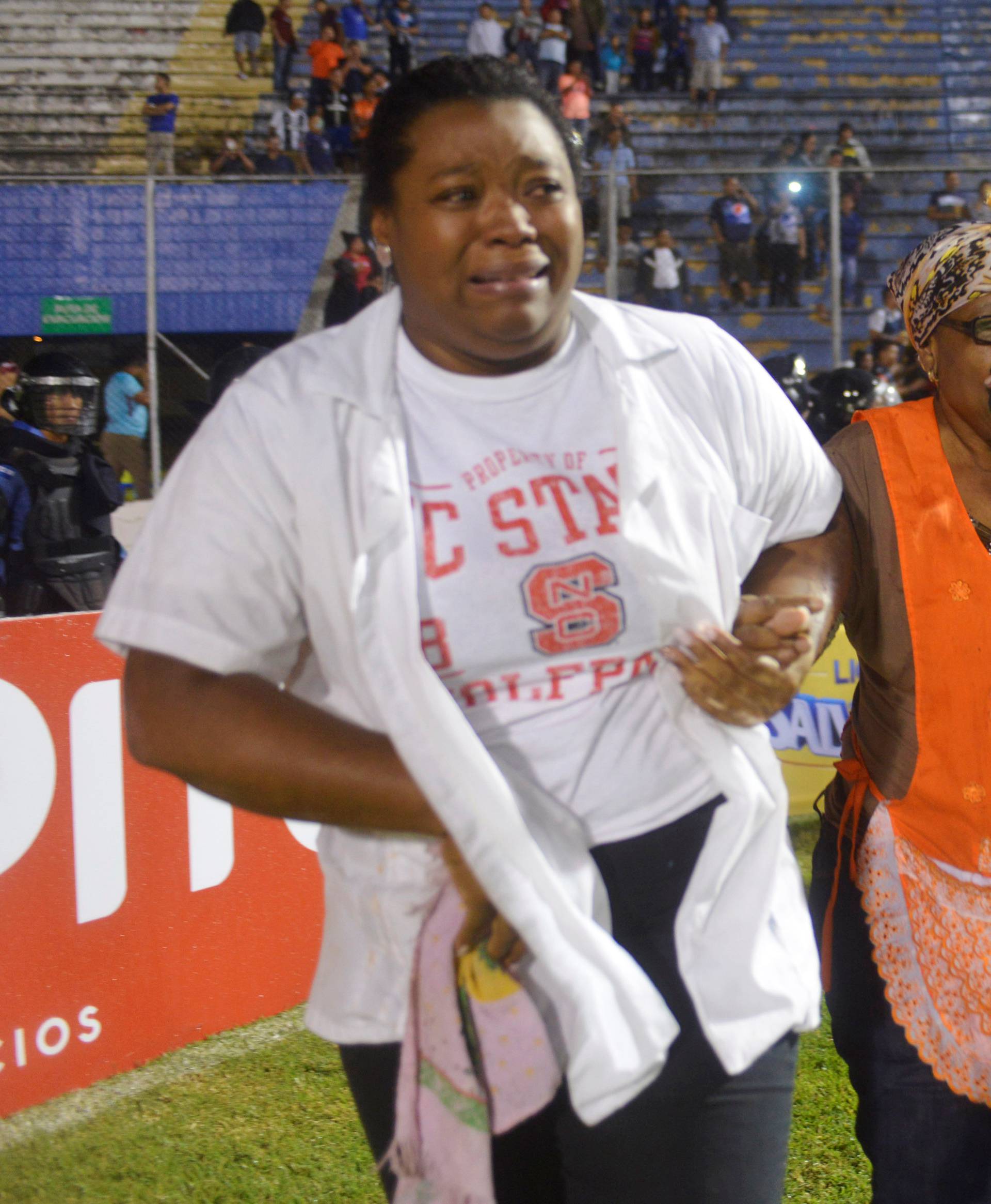 Spectators react from tear gas after three people died in riots before a soccer match when the fans attacked a bus carrying one of the teams, at the National Stadium in Tegucigalpa