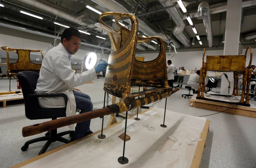 An Egyptian archaeological technician renovates the golden war wheel which belonged to King Tutankhamun, in the conservation centre of the Grand Egyptian Museum, on the outskirts of Cairo