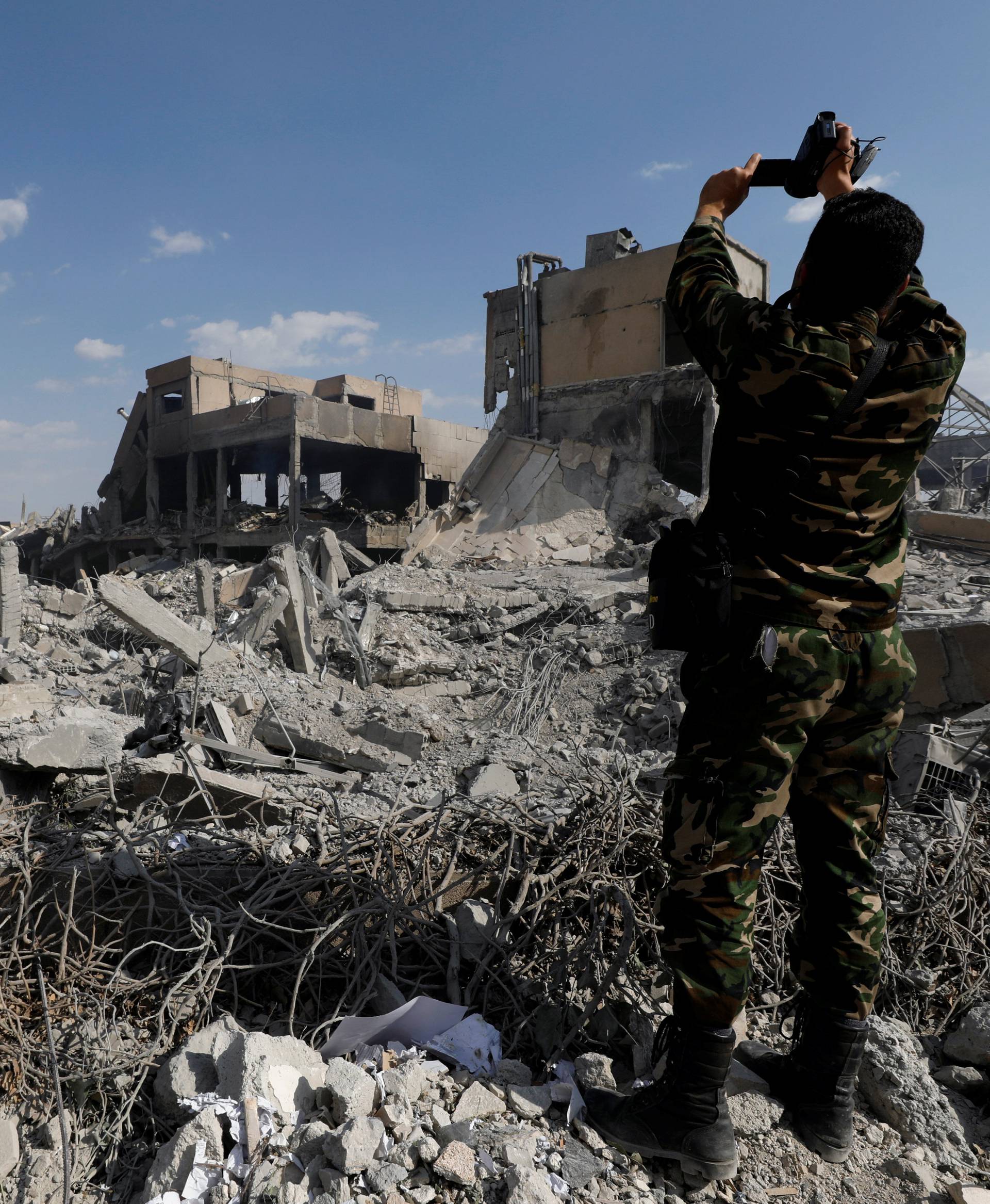 A Syrian military officer records a video inside the destroyed Scientific Research Centre in Damascus