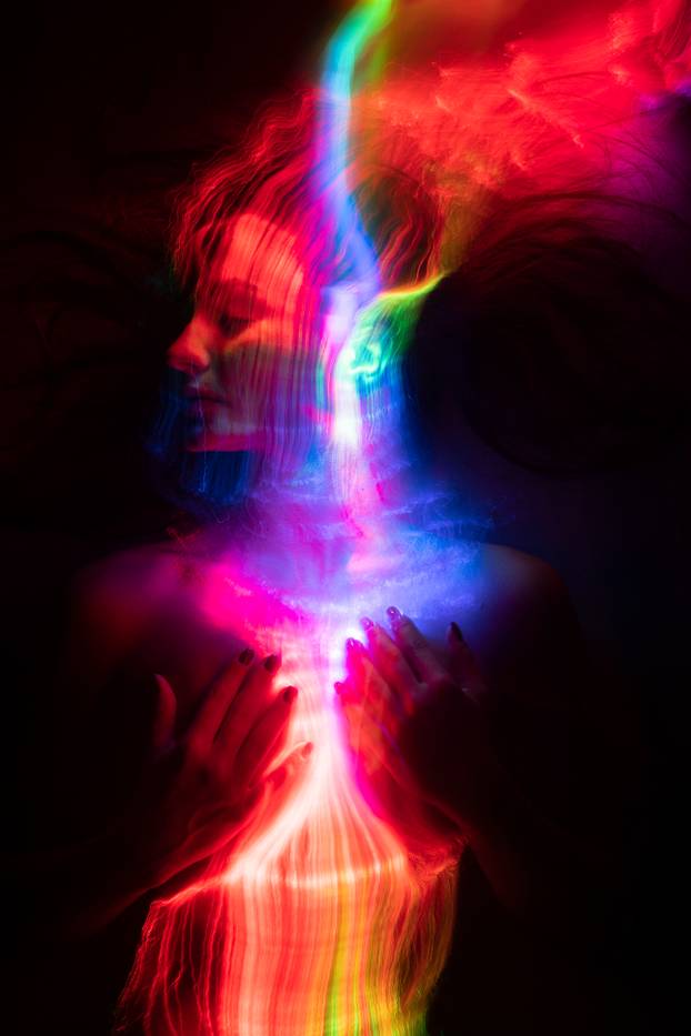 Conceptual avant-garde portrait of a beautiful young girl covered with multicolored lines applied by a light brush. Art style creative photo. Advertising, fashion and commercial design.