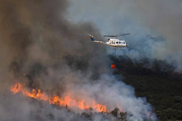 A helicopter works on containing a wildfire during the second heatwave of the year in the vicinity of Guadapero