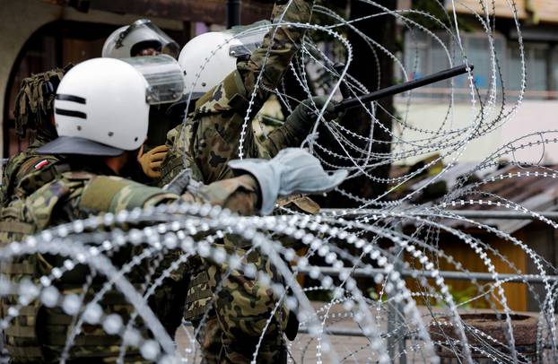 Polish members of the NATO-led Kosovo Force (KFOR) set up a wire fencing as they stand guard near a municipal office in Zvecan