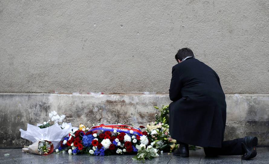 A man pays respects under a commemorative plaque unveiled by French President Francois Hollande and Paris Mayor Anne Hidalgo next to the "Le Carillon" and "Le Petit Cambodge" bars and restaurants in Paris
