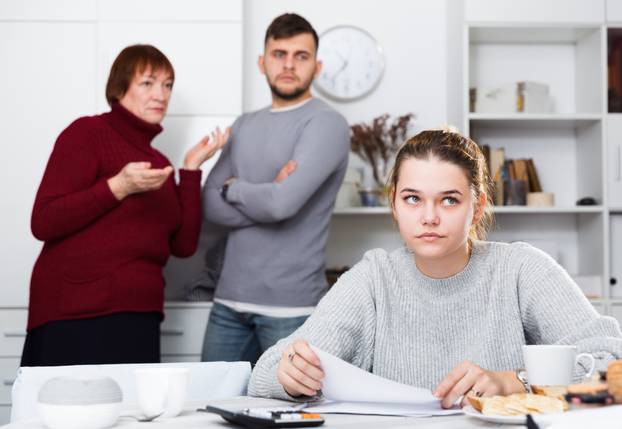 Distressed girl with paperwork and irritated family behind