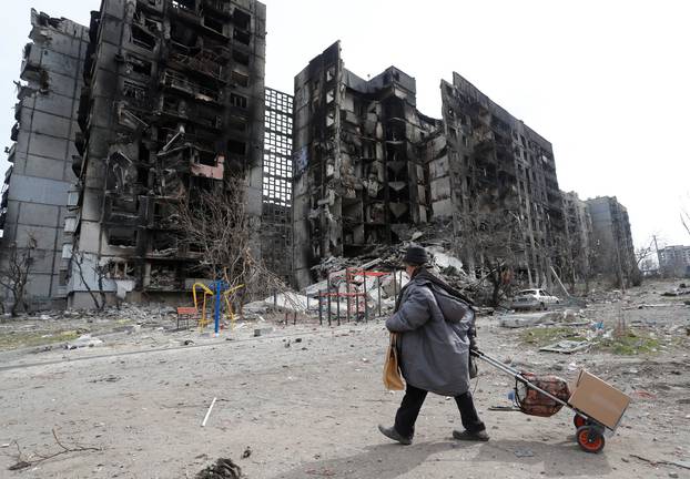 A local resident walks near a destroyed apartment building in Mariupol