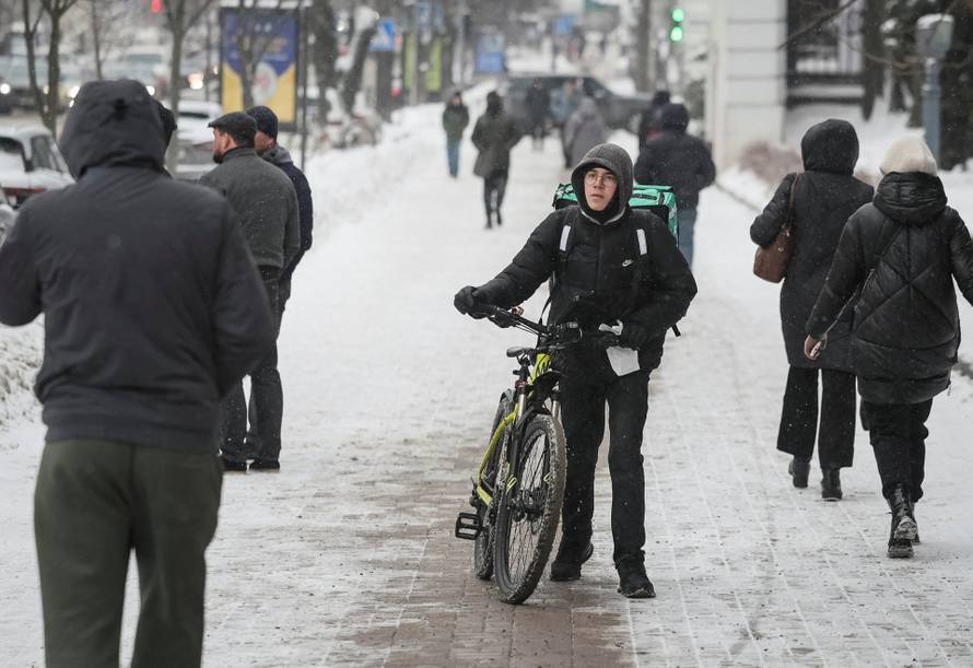 A resident with a bicycle walks on a snow-covered street on a frosty winter day in Kyiv