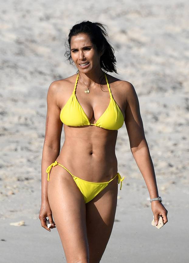 Top Chef host Padma Lakshmi looks amazing in a yellow string bikini as she searches for shells and coral pieces on the beach in Miami