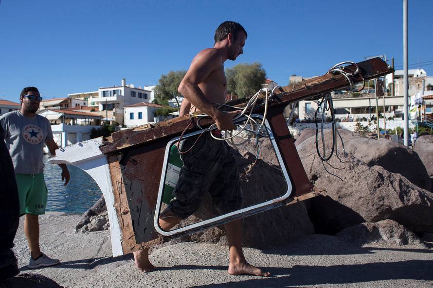 A man carrying a piece of boat, sunk by a speedboat,where four people, including a nine-year-old girl, died and at least five were injured off the Greek island of Aegina close to Athens