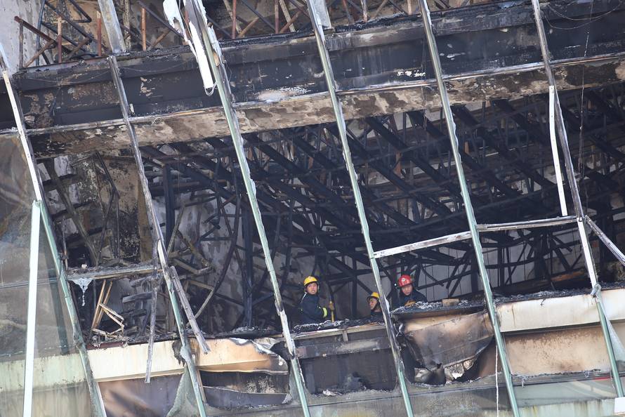 Firefighters inspect the site where a fire broke out at the Shanghai Hongkou soccer stadium in Shanghai