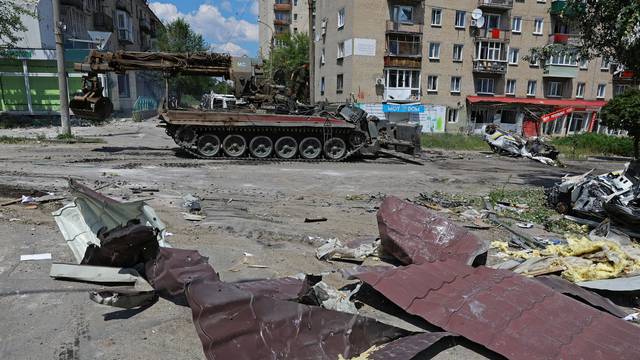 Service members of pro-Russian troops ride on top of a combat engineering vehicle in Lysychansk