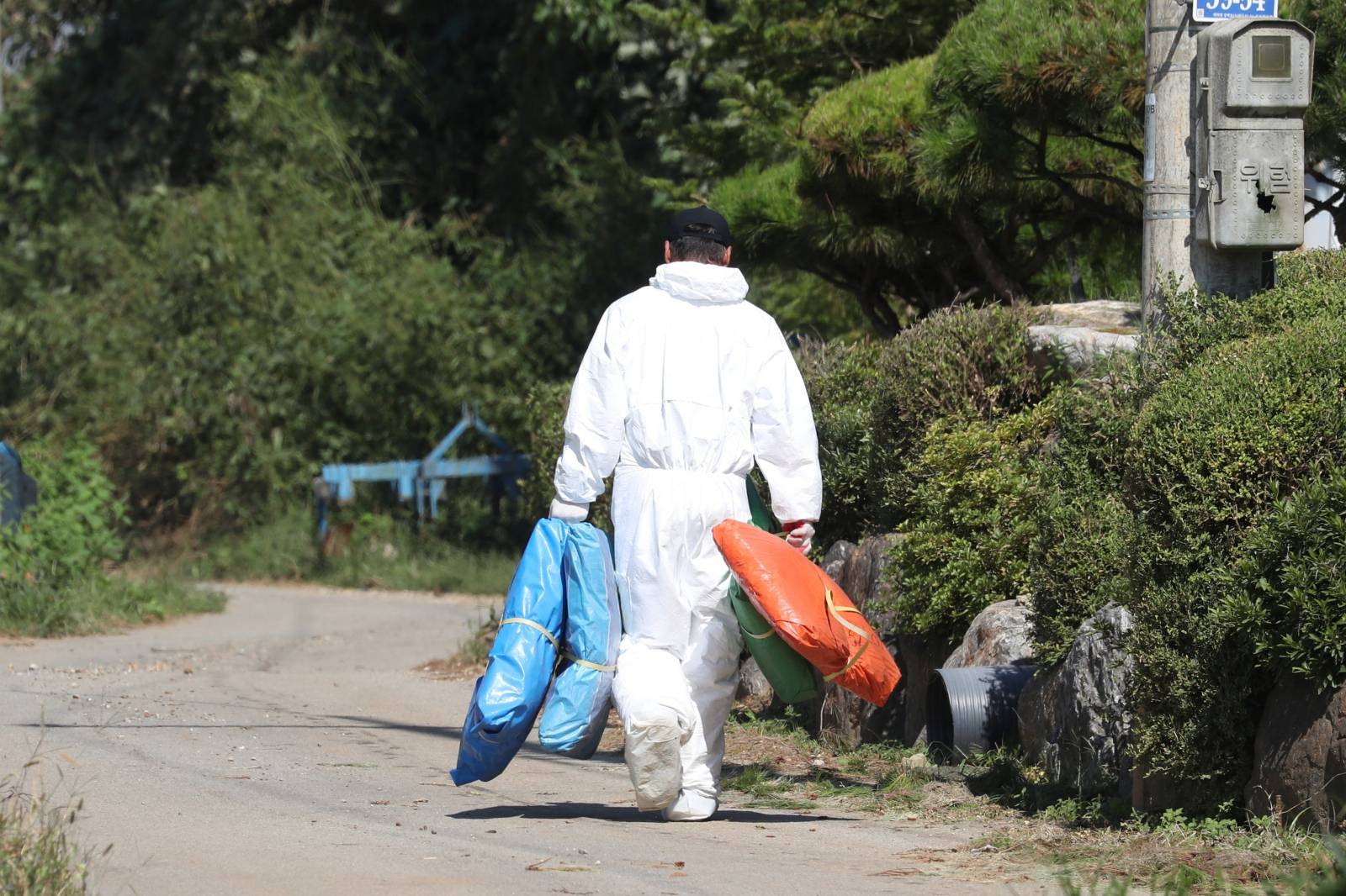 A quarantine official wearing protective gear walks near a pig farm involved in African swine fever in Yeoncheon