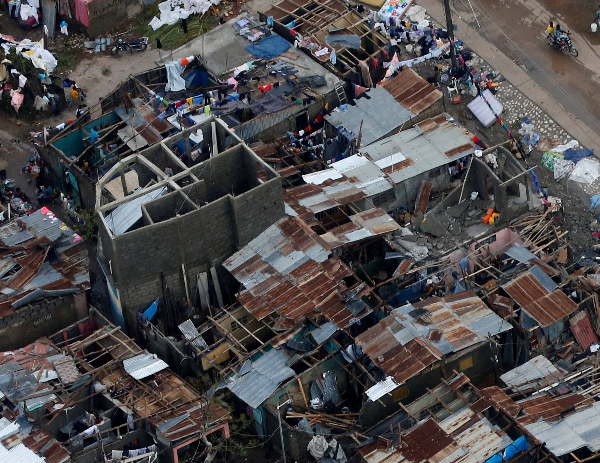 People walk down the street next to destroyed houses after Hurricane Matthew passes Jeremie, Haiti