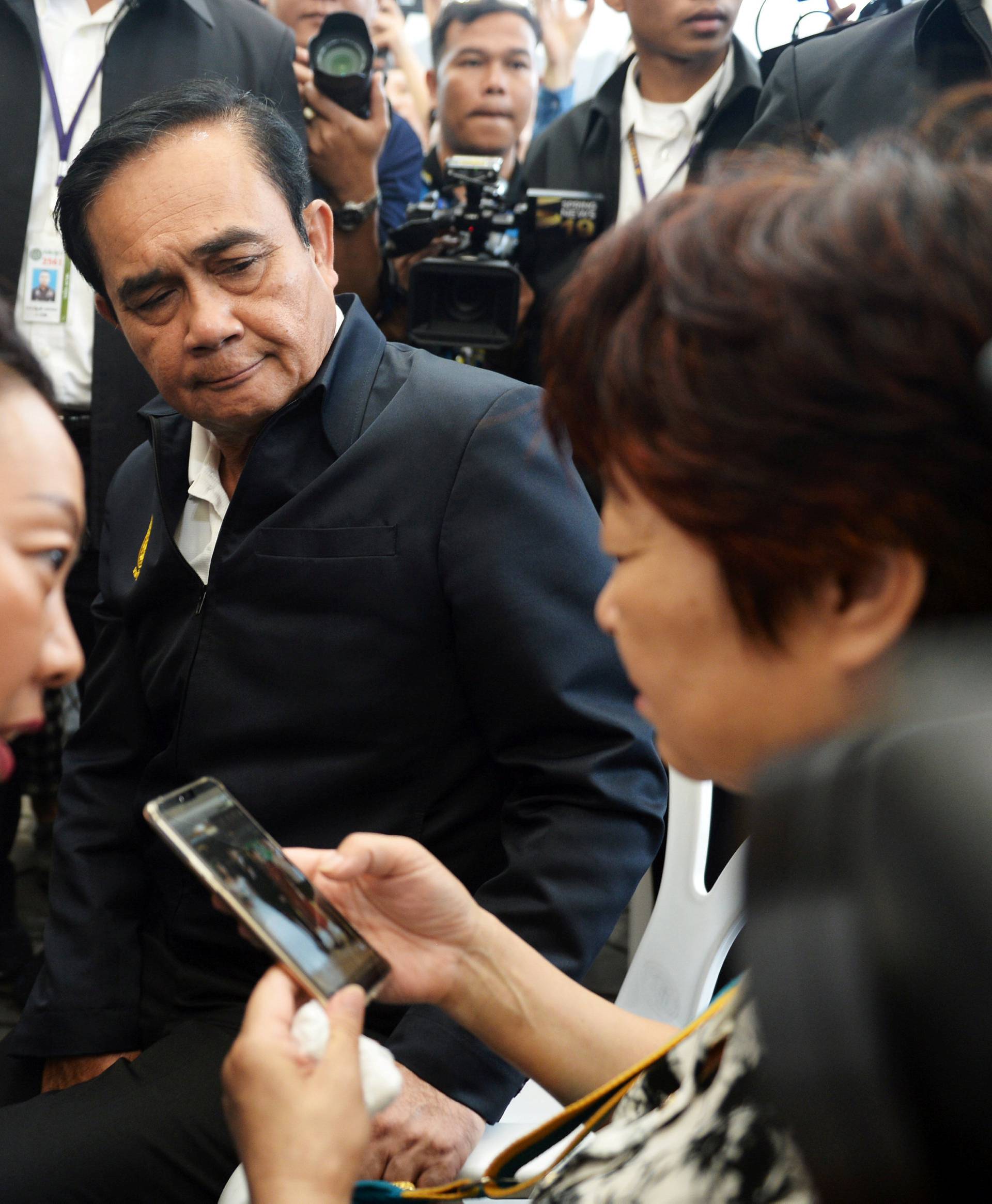 Thailand's Prime Minister Prayuth Chan-ocha sits next to a relative of Chinese tourists involved in a sunken tourist boat accident at a hospital in Phuket