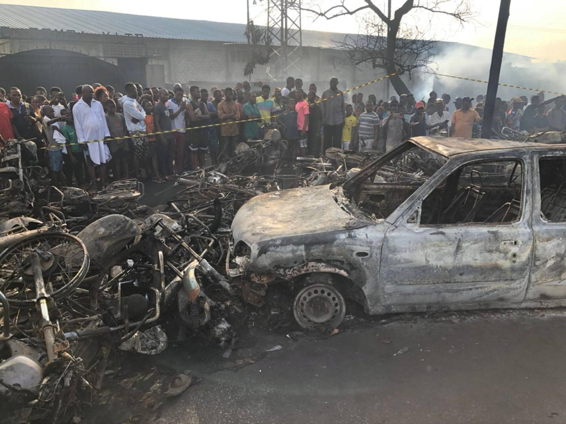 People watch burnt car and motorcycles after a fuel tanker explosion in Freetown