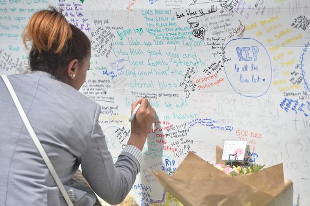 A woman writes on a message wall following the fire that destroyed the Grenfell Tower block, in north Kensington, West London