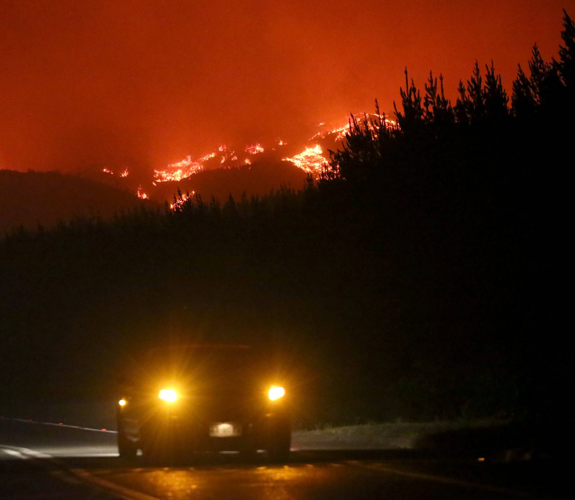 A car is seen near a forest fire in the town of Santa Olga in the Maule region, south of Chile