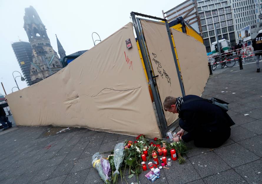 A man lights candles near the scene where a truck ploughed into a crowded Christmas market in the German capital last night in Berlin