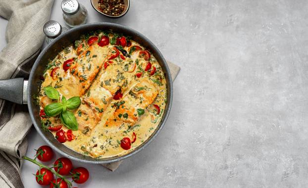 Top view of delicious tuscan cream salmon with spinach in a black pan