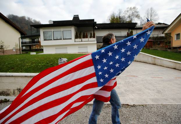 A man carrying the U.S. flag is seen in front of Melania Trump parents