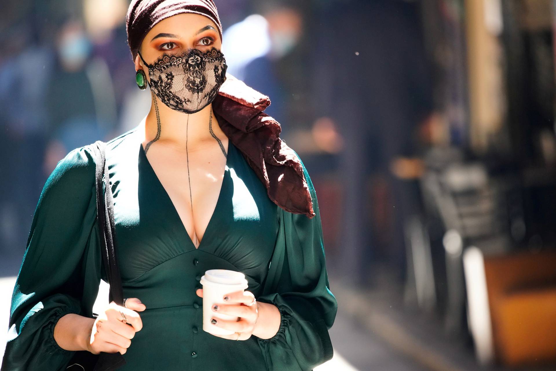 FILE PHOTO: A woman wearing a face masks walks past cafes after coronavirus disease restrictions were eased in Melbourne