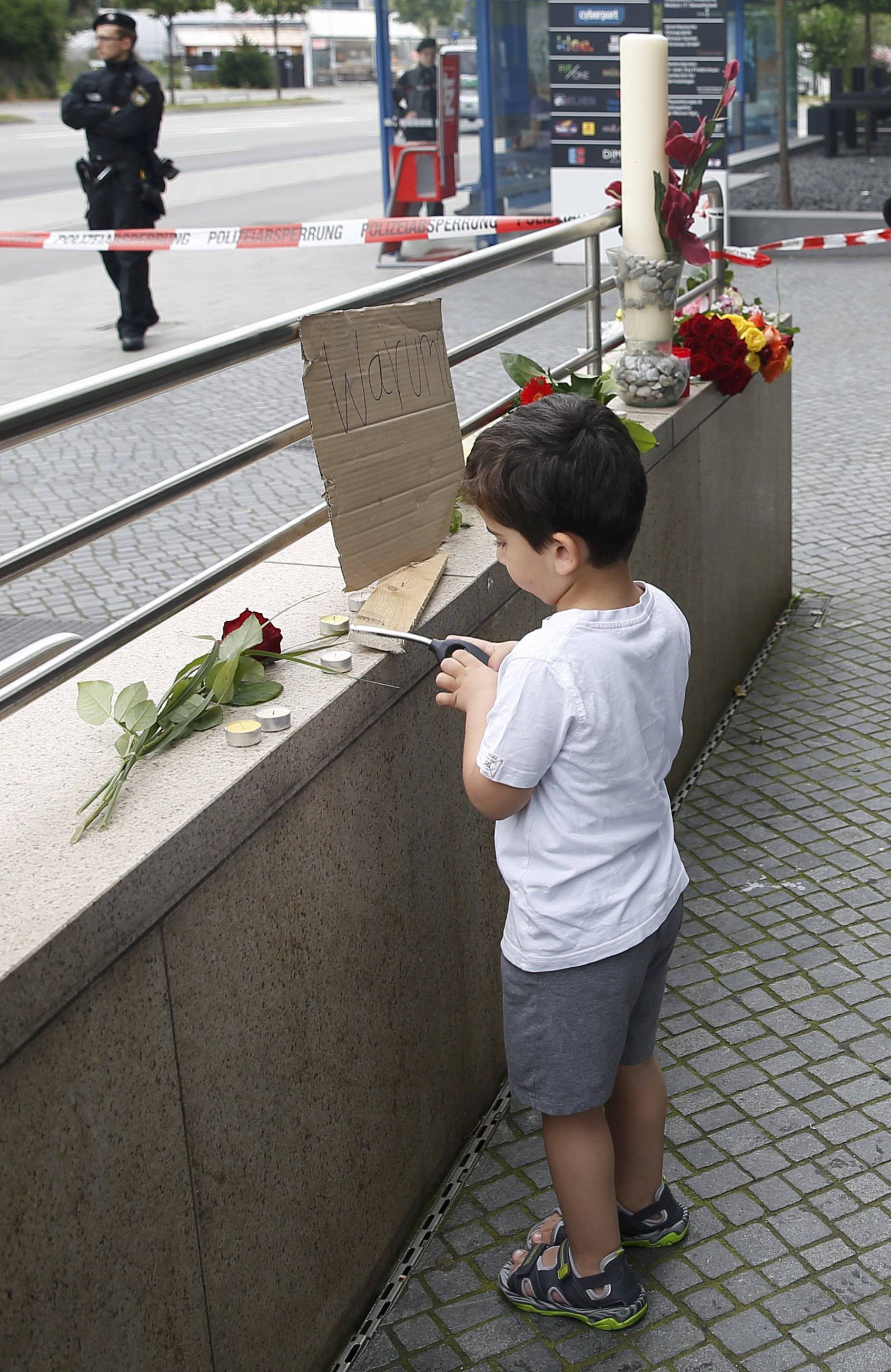 A young boy lights candles on wall near Olympia shopping mall in Munich