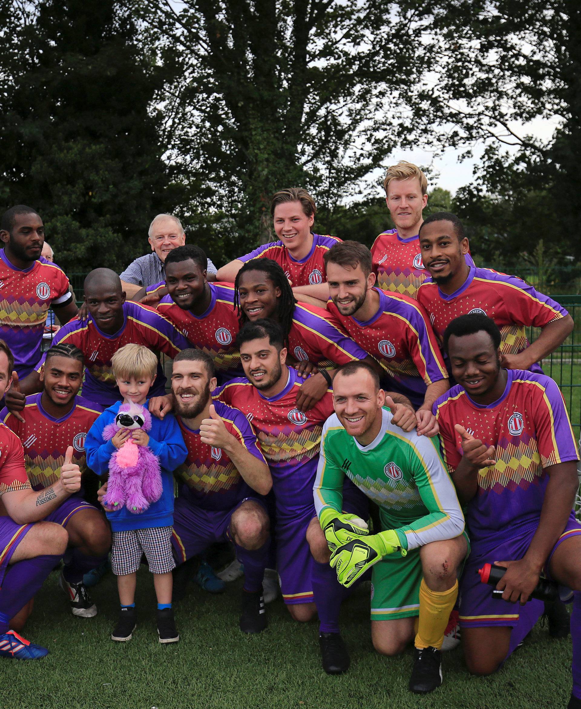 Clapton CFC players pose for a picture with one of their youngest supporter after winning 2-0 away game against Ealing Town in East Acton, in London
