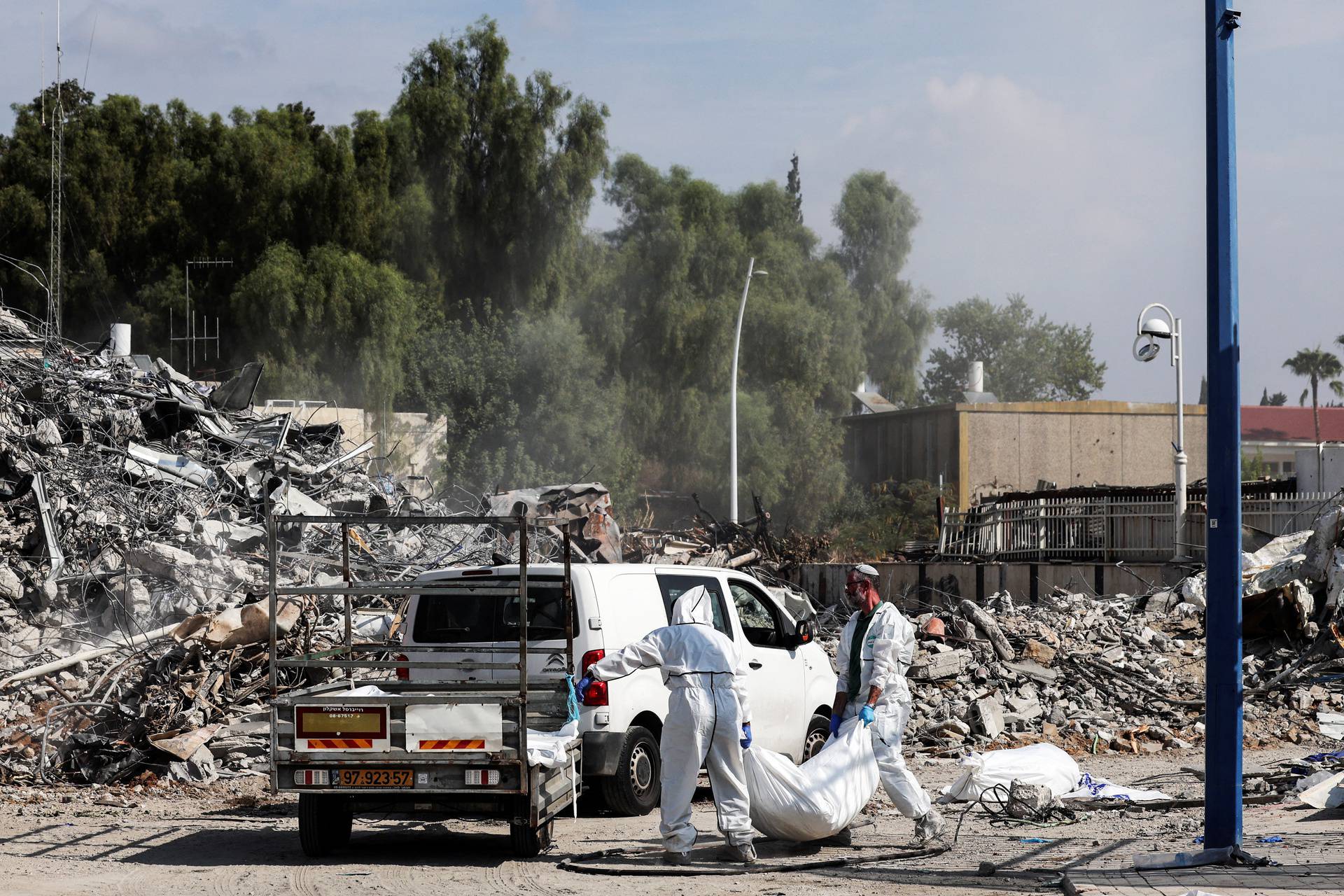 Israeli rescue workers work to remove dead bodies from near a destroyed police station that was the site of a battle following a mass-infiltration by Hamas gunmen from the Gaza Strip, In Sderot