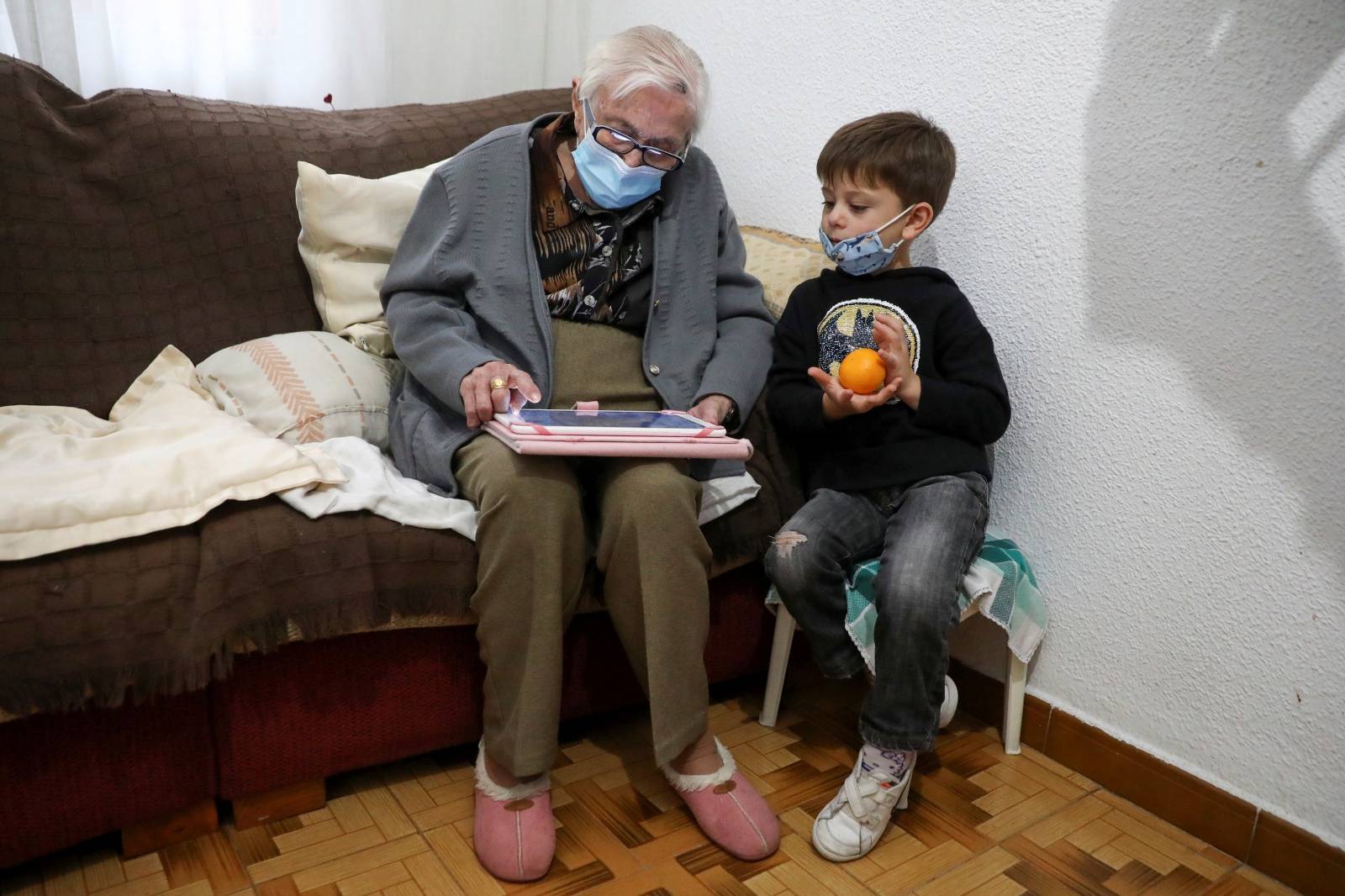 Florentina Martin, a 99 year-old woman who survived coronavirus disease (COVID-19), plays a digital puzzle with her great-grandson Pedro Valle at her home in Pinto