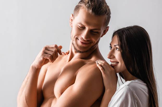 Pretty woman hugging shirtless boyfriend in bedroom