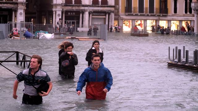 People walk in a flooded Saint Mark Square during a period of seasonal high water in Venice