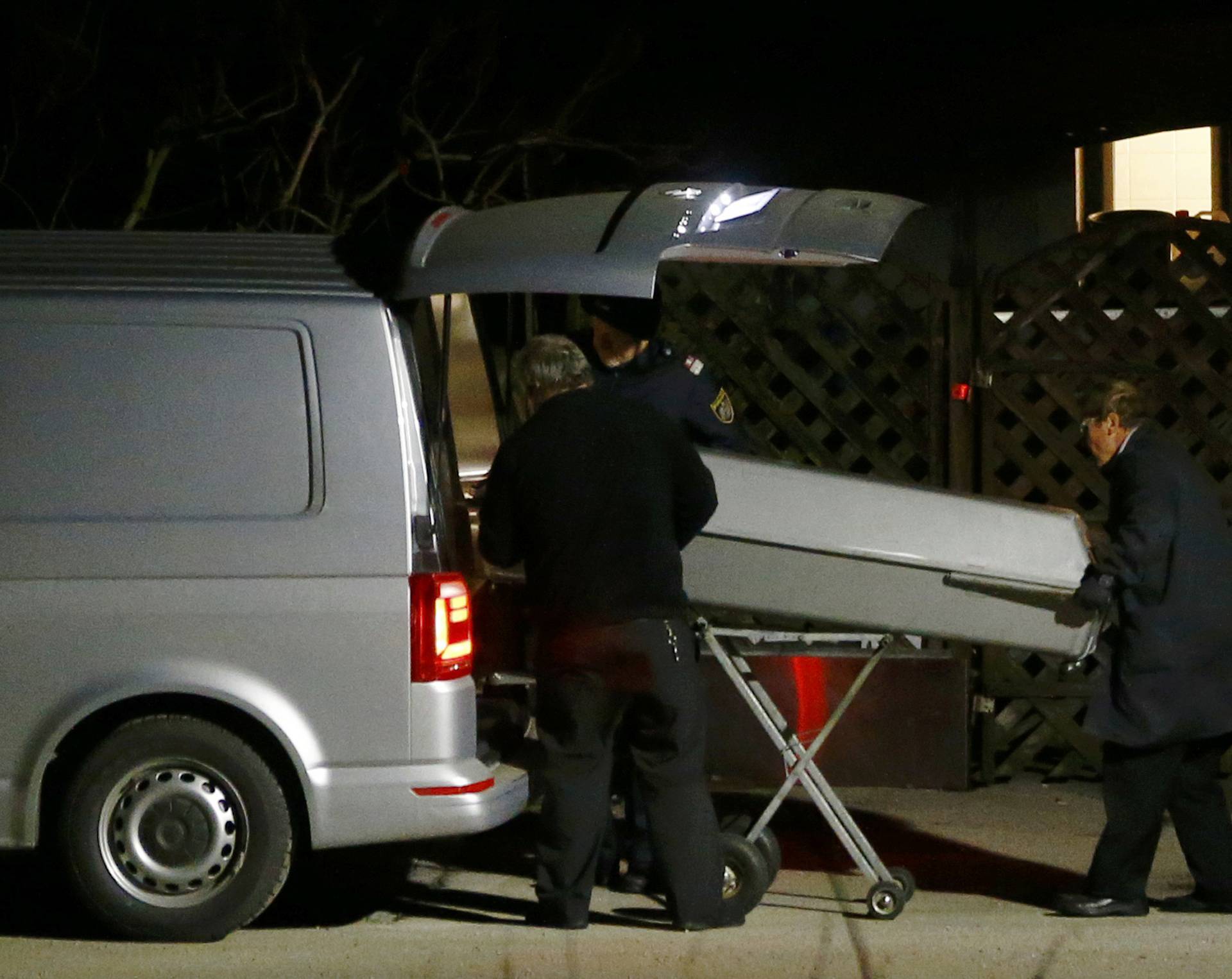 A coffin is loaded nto a hearse outside a house where six people were found dead in Boeheimkirchen