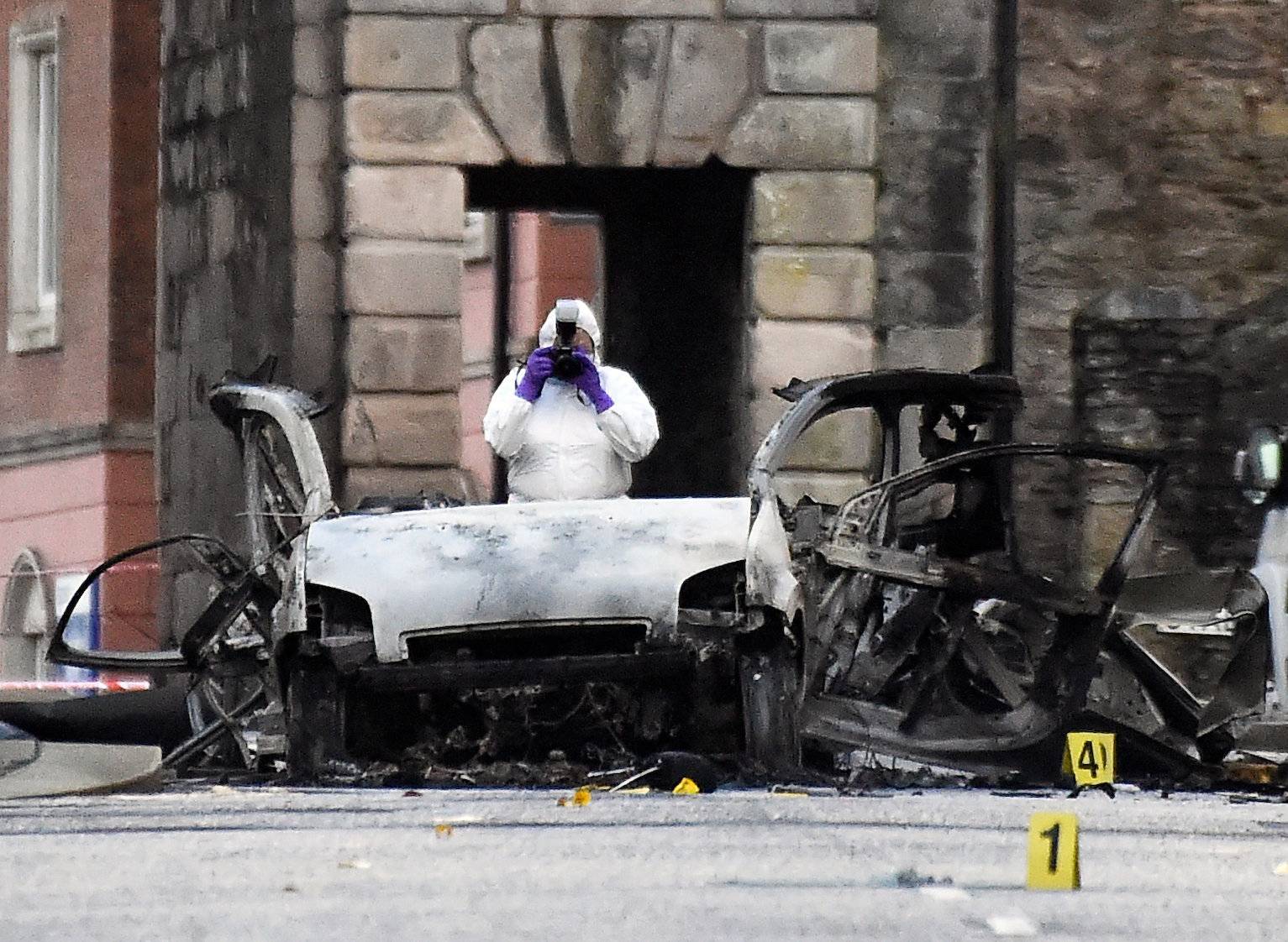 Forensic officer takes a photograph of the scene of a suspected car bomb in Londonderry