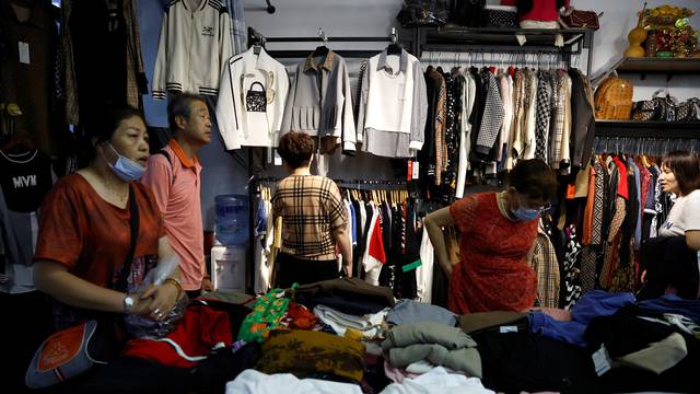 Customers shop clothes at a stall inside a wholesale market in Beijing