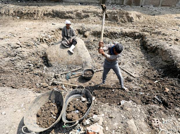 An Egyptian worker unearths a statue that they say likely depicts revered Pharaoh Ramses II who ruled Egypt over 3,000 years ago, at the Matariya area in Cairo
