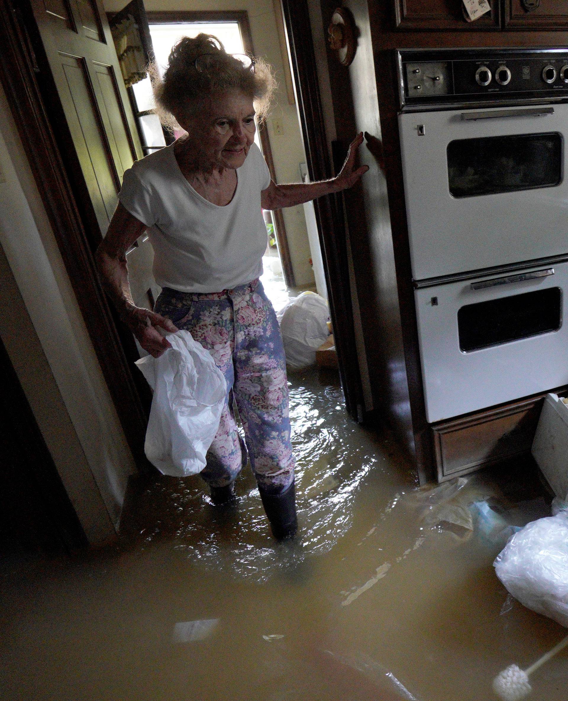 Nancy McBride collects items from her flooded kitchen as she returned to her home for the first time since Harvey floodwaters arrived in Houston