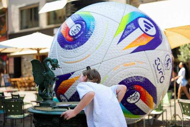 A girl drinks water from a public fountain amid a heatwave, in Basel