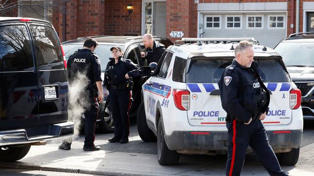 Ottawa Police Service officers surround a home after four children and two adults were found dead inside a neighbouring house in Ottawa