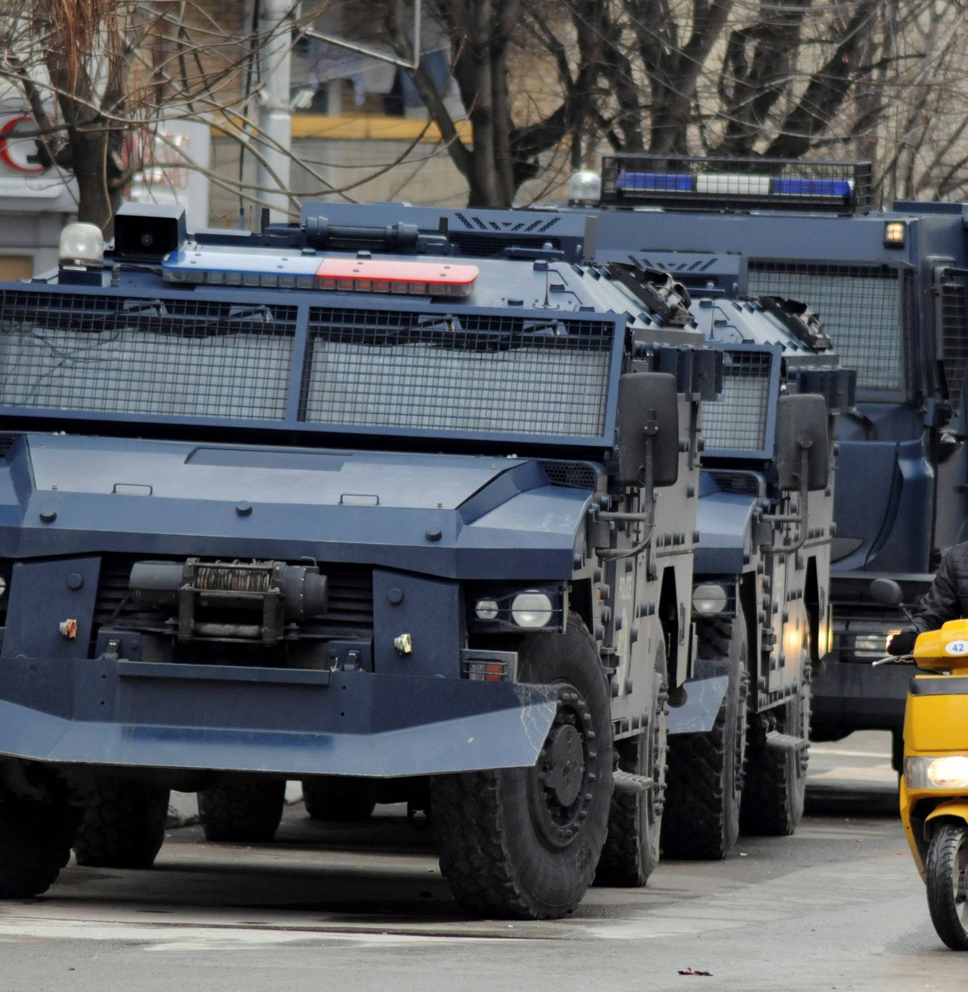 A man rides on a scooter along a street past parked Kosovo police armoured vehicles in southern part of Mitrovica