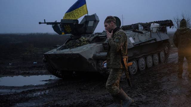 Ukrainian service member smokes next to an armoured personnel carrier on a road in Kherson region