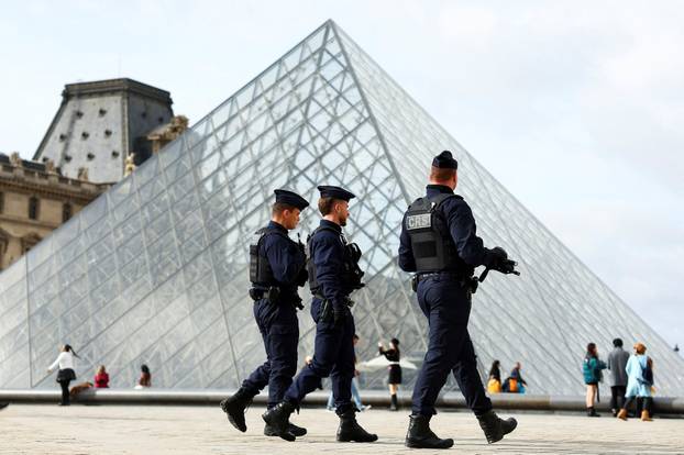 French CRS riot police walk near the glass Pyramid of the Louvre Museum