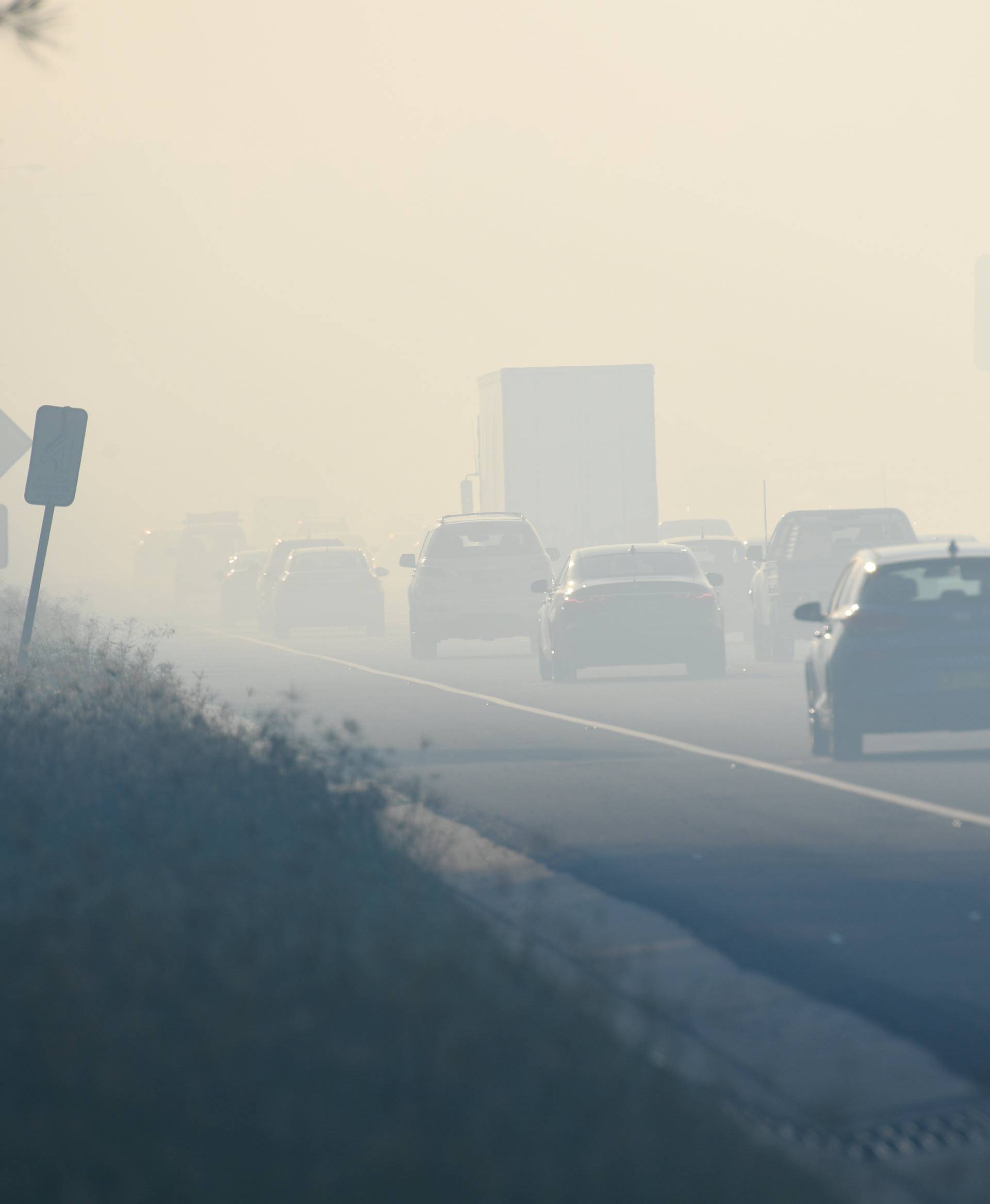 Motorists drive through smoke caused by bushfires on the M5 in Sydney