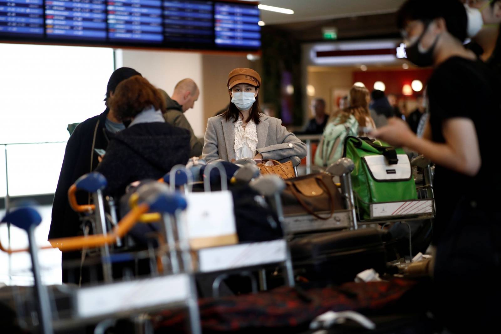 Travellers wearing masks arrive on a direct flight from China, in Paris