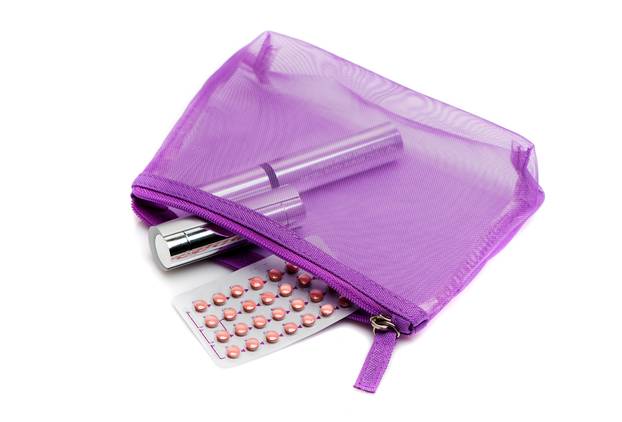 Oral ?ontraceptive pills, cosmetic bag, mascara and lipstick on a white background. Medicine concept, flat lay