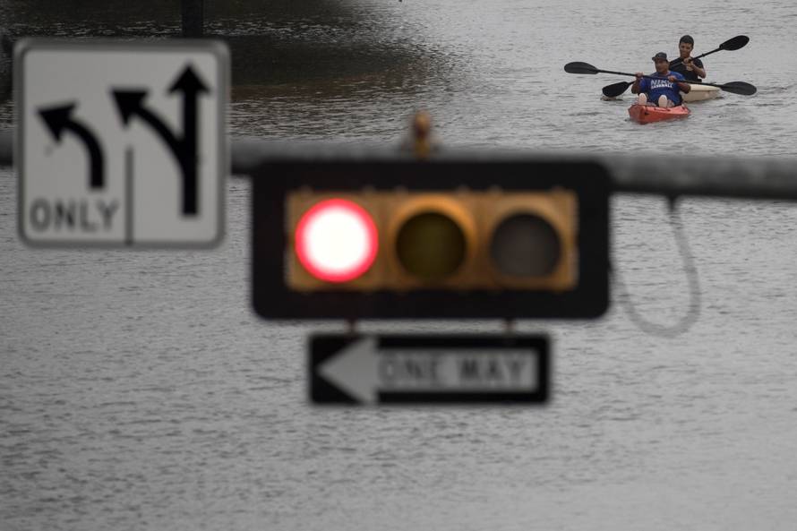 Men use kayaks to get through an intersection after heavy rain from Hurricane Harvey flooded Pearland, in the outskirts of Houston